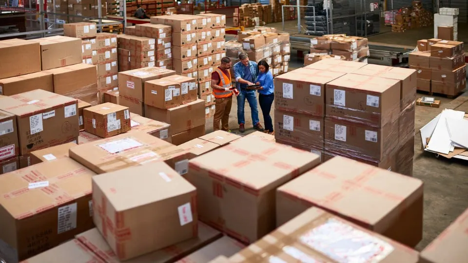 group of co-wrkers in a large warehouse full of boxes