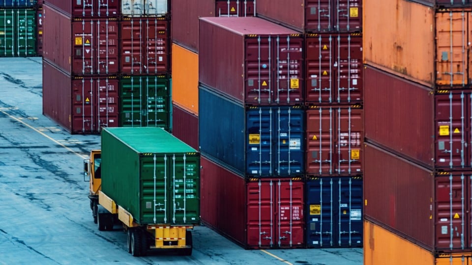 Tractor trailer truck hauling a shipping container at container ship yard