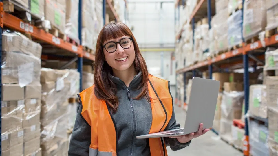 lady holding a laptop standing in a warehouse