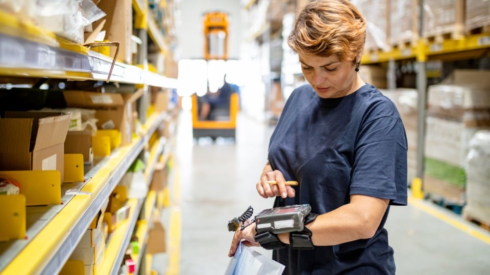 Woman in warehouse pushing buttons on wearable barcode reader