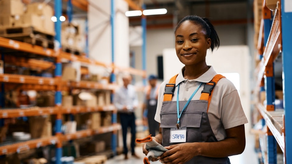 Happy female worker at distribution warehouse looking at camera