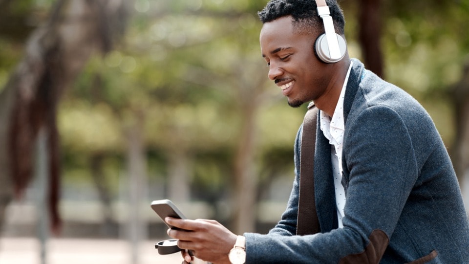 businessman using a smartphone and headphones in the park