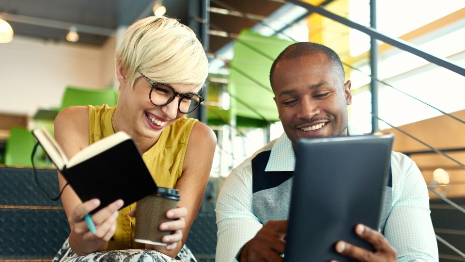 Two business professionals holding tablets and laughing