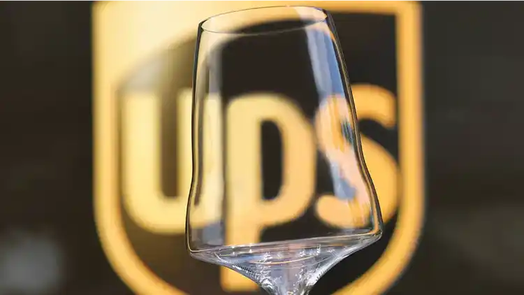 Fine glassware product held in front of the U-P-S logo.